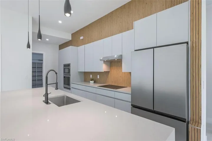 Kitchen featuring an expansive white countertop island with an undermount sink and matte black pull-down faucet
