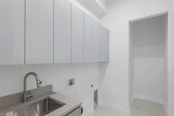 Laundry area featuring a stainless steel utility sink, pull-down faucet, and gray countertop