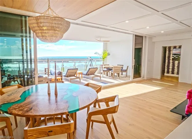 Dining room with a water view, a notable chandelier, wood-type flooring, and a wall of windows