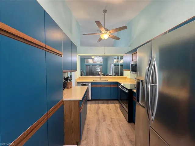 Kitchen featuring stainless steel appliances, light wood-style flooring, blue cabinets, light countertops, and ceiling fan