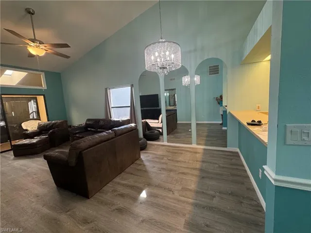 Dinning  room featuring high vaulted ceiling, wood finished floors, arched walkways, a chandelier, and a ceiling fan