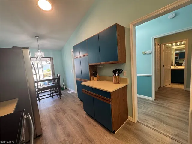 Kitchen featuring appliances with stainless steel finishes, light wood-style floors, light countertops, blue cabinetry, and decorative light fixtures