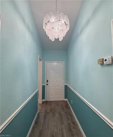 Doorway with wood finished floors and a chandelier