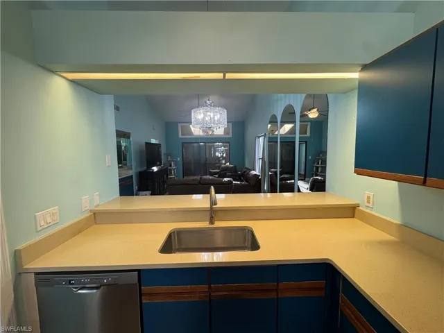 Kitchen featuring a chandelier, dishwasher, light stone counters, open floor plan, and ceiling fan