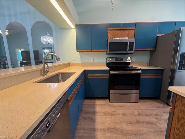 Kitchen with blue cabinets, stainless steel appliances, light wood-style flooring, and a ceiling fan