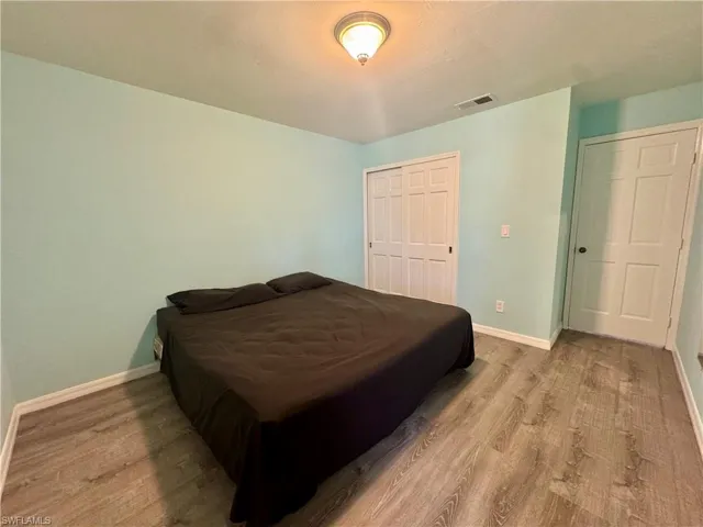 Bedroom with wood finished floors and a closet