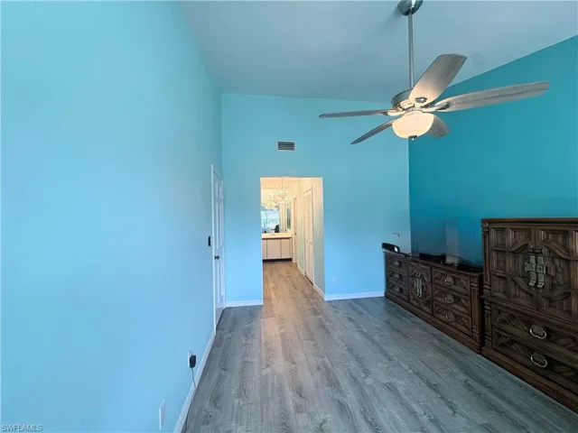 Unfurnished bedroom with wood finished floors, ceiling fan, and high vaulted ceiling