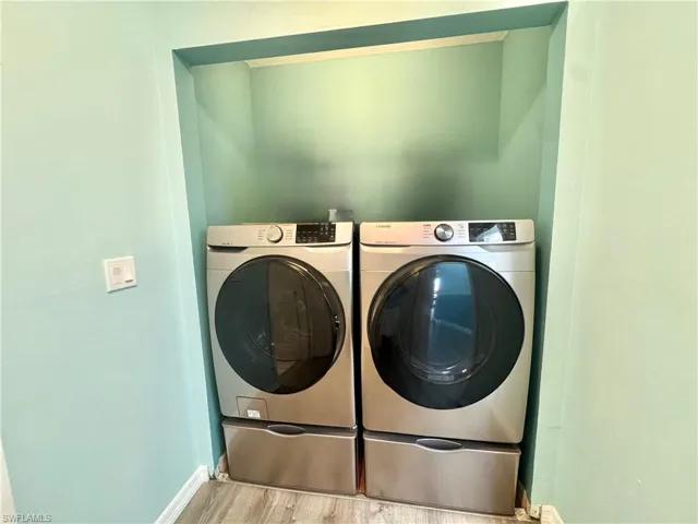 Laundry area with wood finished floors and washing machine and dryer