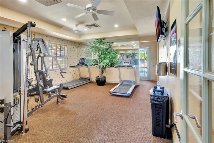 Workout room with carpet floors, ceiling fan, recessed lighting, wallpapered walls, and a raised ceiling