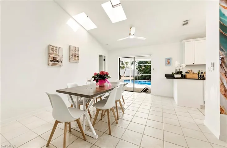 Dining room featuring a skylight, a ceiling fan, vaulted ceiling, and light tile patterned floors