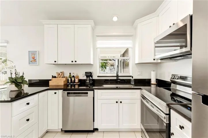 Kitchen featuring stainless steel appliances, white cabinets, a peninsula, dark stone counters, and recessed lighting