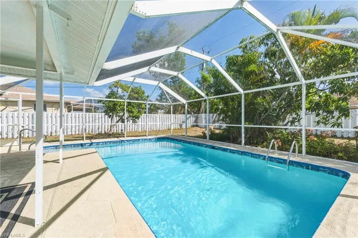 View of swimming pool with glass enclosure, a fenced backyard, patio surround, and a sunroom