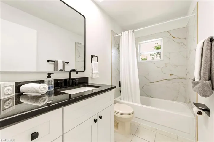 Full bath with vanity, a combined bath / shower with marble appearance, and light tile patterned floors