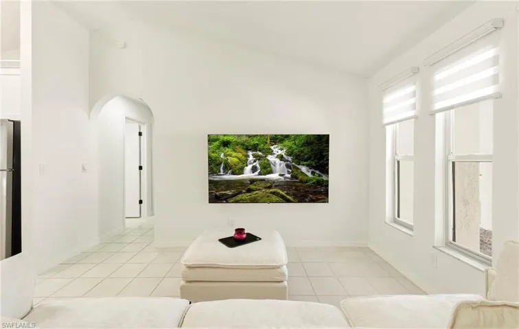 Living room with arched walkways, vaulted ceiling, and light tile patterned flooring