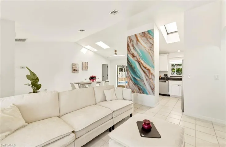 Living room featuring a skylight, vaulted ceiling, and light tile patterned floors