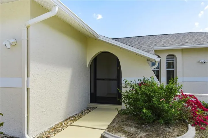 Doorway to property featuring stucco siding and roof with shingles