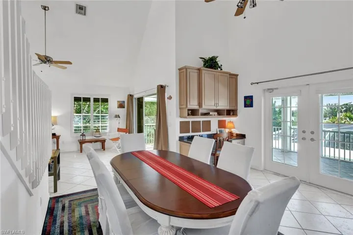 Dining area featuring vaulted ceilings, light-finish tile flooring, and a built-in wet bar with wood-finish cabinetry