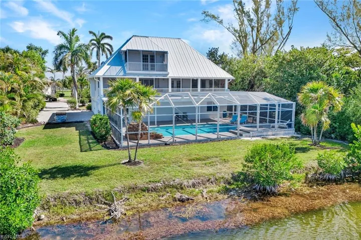 Two-story waterfront residence featuring a screened-in pool and an upper-level balcony