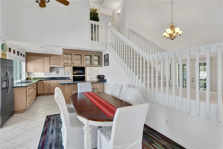 Two-story interior featuring a kitchen with wood cabinetry, dark countertops, and a white tile backsplash