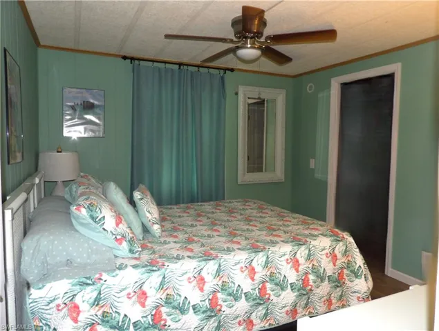 Bedroom featuring crown molding, a ceiling fan, and luxury vinyl flooring