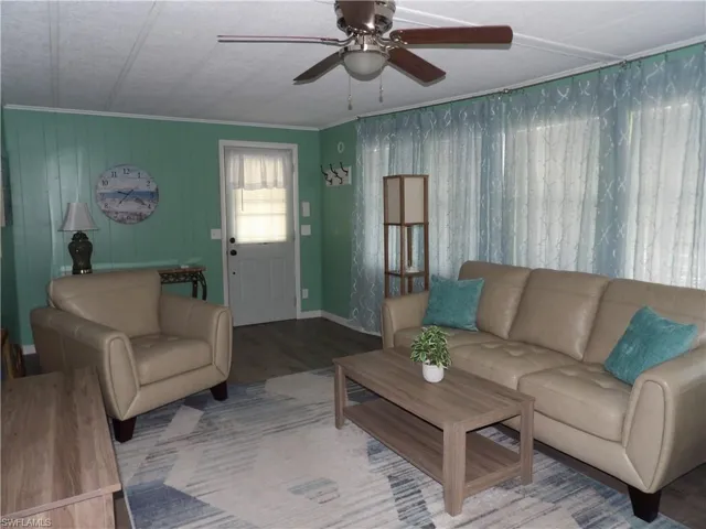 Living area featuring wood finished floors, ceiling fan, and crown molding