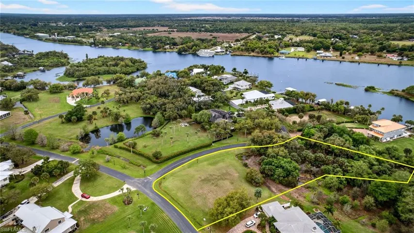 Aerial view of residential area with a nearby body of water and property boundaries highlighted