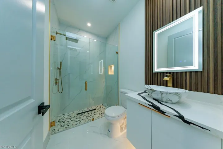 Bathroom with a marble finish shower, vanity, marble finish flooring, and recessed lighting