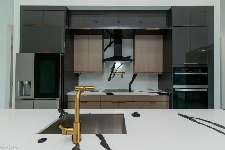 Kitchen with black appliances, wall chimney range hood, modern cabinets, and gray cabinetry