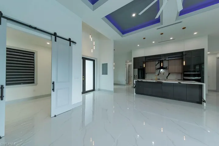 Kitchen with a barn door, modern cabinets, light marble finish flooring, recessed lighting, and a high ceiling