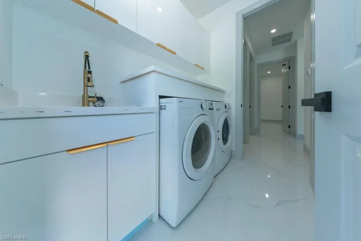Washroom featuring independent washer and dryer and light marble finish flooring