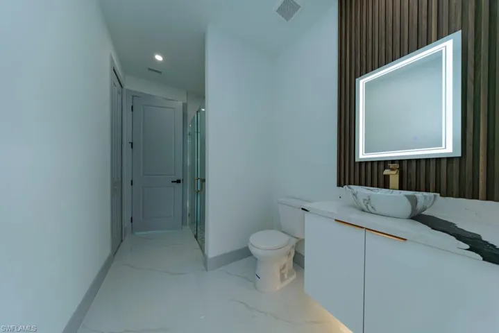 Full bath with marble finish flooring, vanity, a stall shower, and recessed lighting