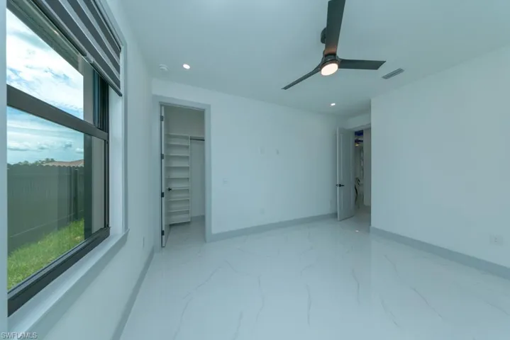 Empty room featuring light marble finish flooring, recessed lighting, ceiling fan, and a smoke detector