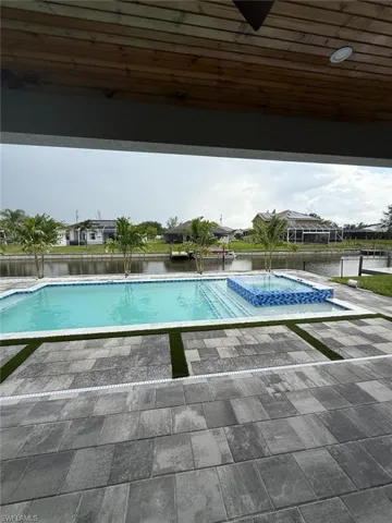 View of swimming pool with a patio, a pool with connected hot tub, and a water view