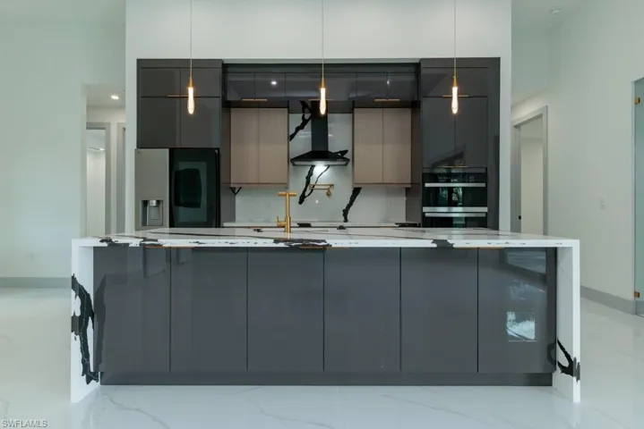 Kitchen with wall chimney exhaust hood, fridge with ice dispenser, modern cabinets, and gray cabinetry