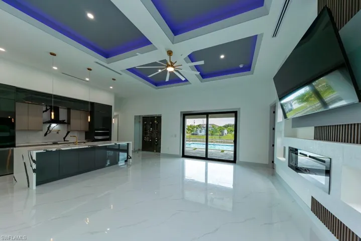 Living area featuring coffered ceiling, recessed lighting, light marble finish flooring, ceiling fan, and beamed ceiling