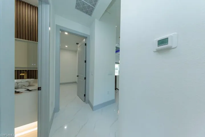 Corridor with marble look tile flooring and baseboards