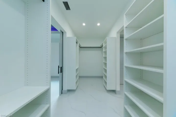 Walk in closet featuring light marble finish floors