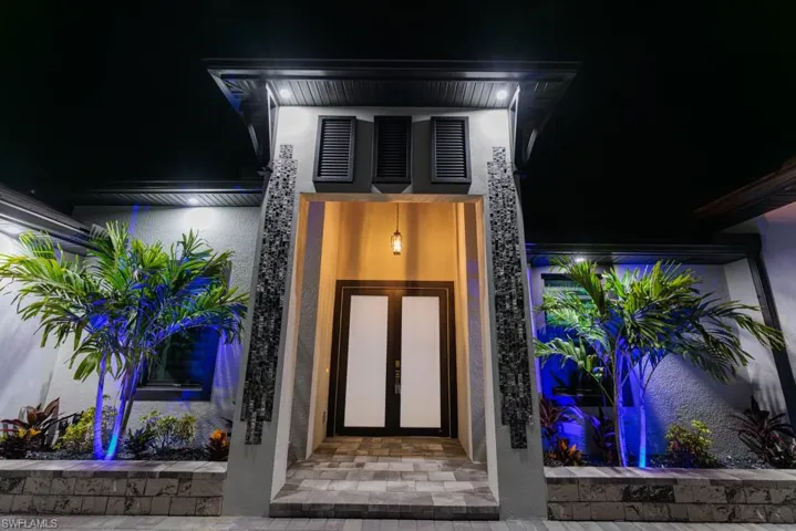 Exterior entry at night featuring stucco siding