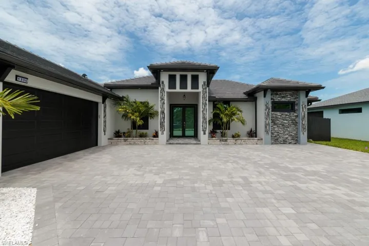 Prairie-style house with stucco siding, driveway, a tile roof, and french doors