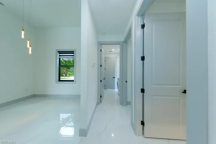 Hall featuring light marble finish flooring and baseboards