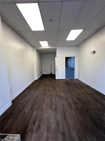 Spare room with dark wood-type flooring and a paneled ceiling