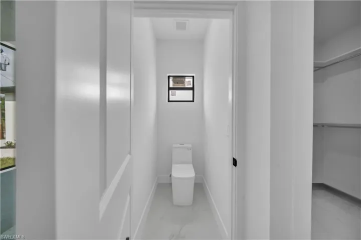 Bathroom featuring light marble finish floors and toilet