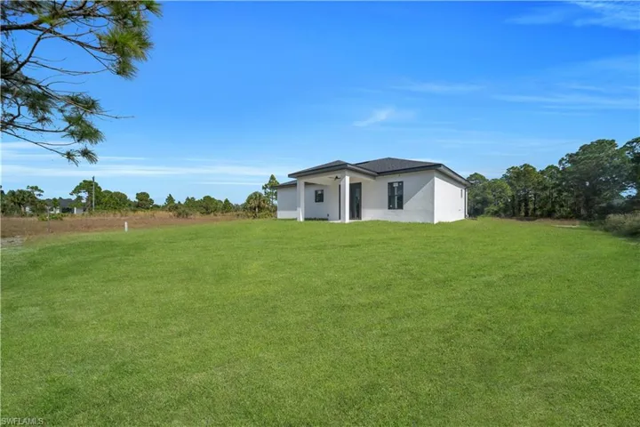 Back of property featuring a lawn and stucco siding