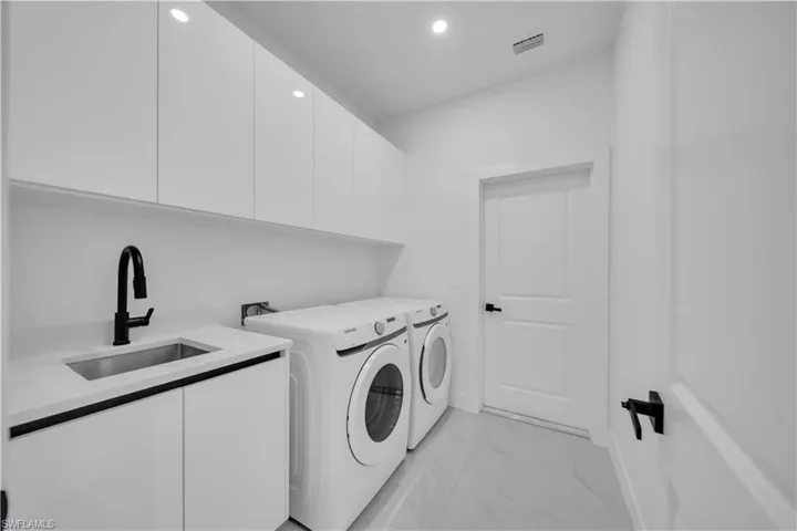 Laundry area with cabinet space, recessed lighting, washing machine and dryer, and light marble finish flooring