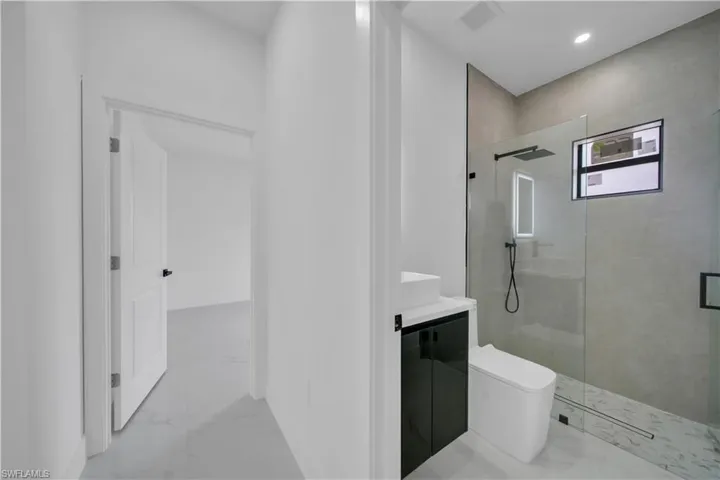 Full bathroom featuring vanity, a walk in shower, light marble finish floors, and recessed lighting