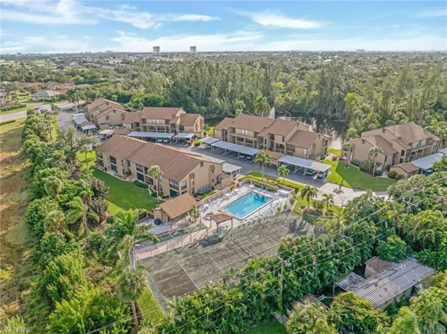 Aerial perspective of suburban area featuring a pool and a tree filled landscape