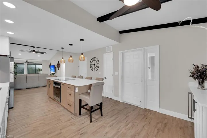 Kitchen with a ceiling fan, pendant lighting, light wood-style floors, a kitchen breakfast bar, and open floor plan