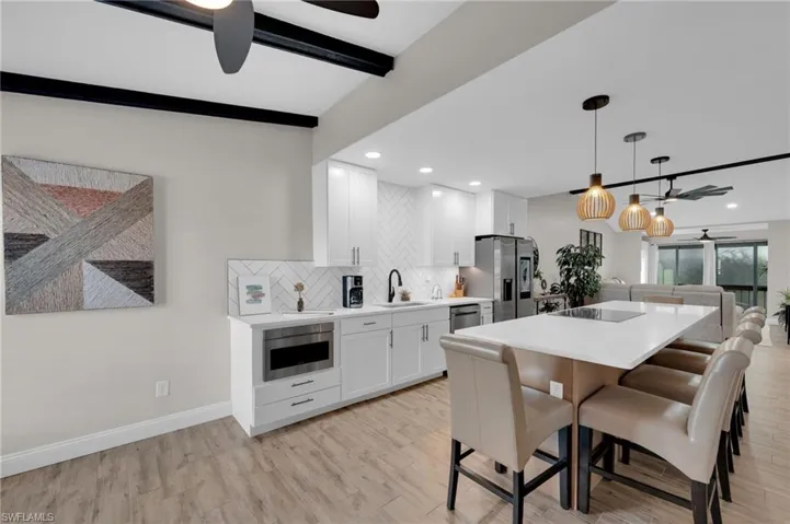 Kitchen with ceiling fan, beam ceiling, pendant lighting, backsplash, and a center island