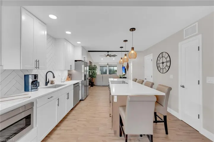 Kitchen with a kitchen bar, white cabinets, stainless steel appliances, recessed lighting, and light quartz countertops