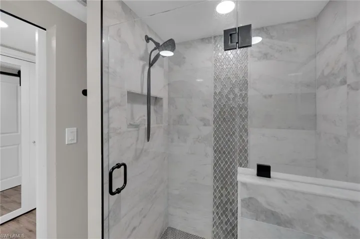 Full bathroom with a marble finish shower and recessed lighting